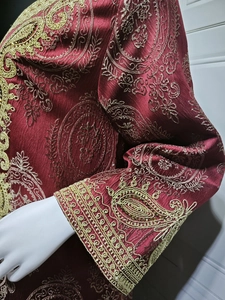 Détail du tissu kaftan bordeaux avec broderie paisley dorée et poignets en dentelle
