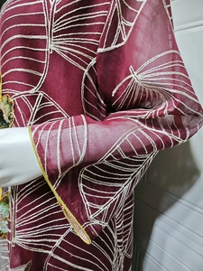 Dettaglio ravvicinato di un abito in rete bordeaux con eleganti ricami geometrici