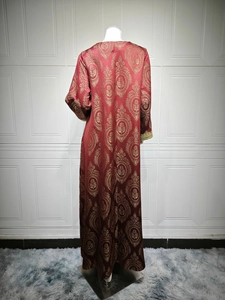 Détail du dos d'une robe caftan rouge avec motifs jacquard dorés et poignets en dentelle