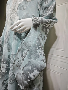 Detail of light blue embroidered dress with white sequins and vintage floral patterns