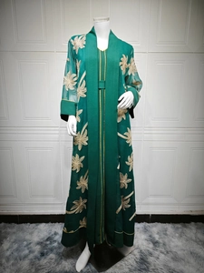 Detail of dark green abaya with intricate golden palm leaf embroidery and gold piping