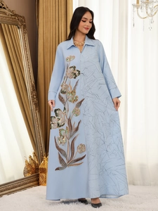 Detail view of intricate floral sequin embroidery on light blue jacquard fabric