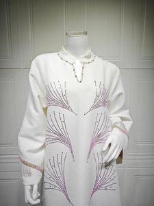 Detail of beaded mock neck dress with sparkling rhinestone starburst and textured fabric