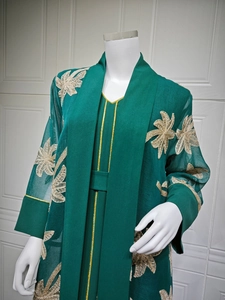 Close-up of golden leaf embroidery on dark green abaya fabric with vertical texture
