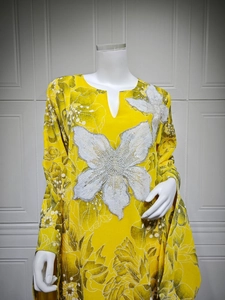 Detail of white sequined floral appliques on a yellow linen dress with green flower print