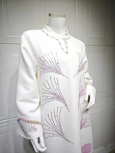 Detail of white textured dress with pink floral embroidery and pearl neckline accents