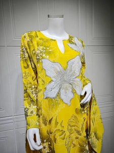 Close-up of intricate white sequin floral embroidery on a yellow printed dress