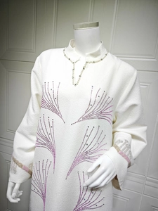 Detail of white crepe dress with beaded collar and purple sequin feather patterns