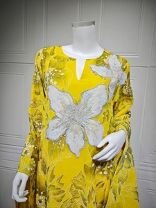 Detail of white sequin floral embroidery on a yellow long-sleeved dress with green print