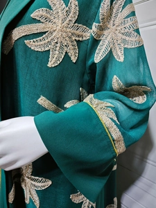 Close-up of teal tulle cardigan featuring intricate gold floral embroidery and textures