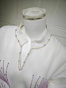 Detailed view of pearl-embellished V-neckline with sparkling crystal rhinestone patterns