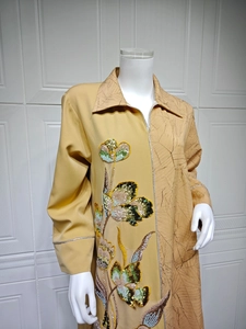 Detail of yellow kaftan showing intricate sequin floral embroidery and leaf textures