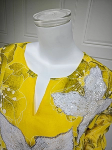Detailed view of the yellow V-neck top featuring sequin flower applique and floral print