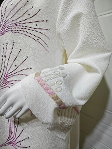 Detail of white jacquard kaftan showing purple rhinestones and embroidered cuffs