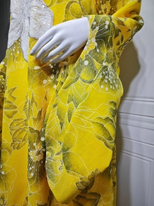 Detail of yellow floral dress with intricate white sequin embroidery and lace applique
