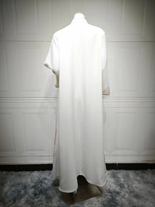 Back view of a white kaftan dress featuring colorful floral embroidery on the sleeve and hem