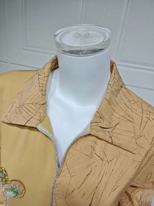 Detail of yellow sequin embroidery on collar with black leaf pattern and silver trim