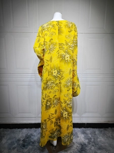 Detail of yellow long sleeve dress featuring green floral embroidery on white mannequin