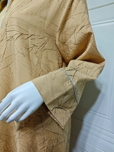 Detail of mustard yellow jacquard dress with pleated leaf texture and silver trim cuffs