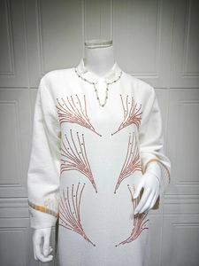 Detail of white jacquard dress featuring pearl collar and orange rhinestone pattern