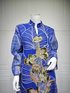 Dettaglio di un elegante abito in rete blu con ricami etnici floreali e paillettes lucide
