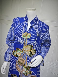 Dettaglio dell'abito in rete blu con intricati ricami floreali di paillettes e motivi a foglia.