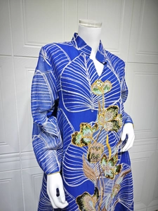 Dettaglio di un abito in tulle blu con ricami floreali di paillettes e motivi di foglie.