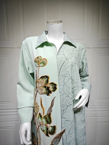 Close-up of light green dress with floral sequin embroidery and pleated texture detail