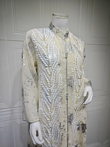 Detail der Stickerei am beigen Kaftan mit silbernem Blumendruck und Stehkragen