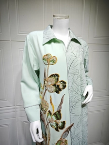 Detailed mint green dress showing floral sequin embroidery and textured leaf fabric