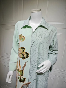 Detail of mint green ethnic dress featuring floral sequin embroidery and leaf texture