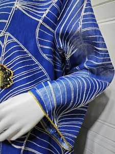 Primo piano di un abito etnico in rete blu con ricami bianchi e dettagli in paillettes