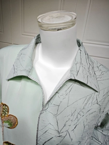 Detail of light green sequined butterfly embroidery and dark branch pattern on a dress