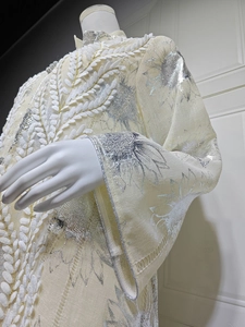 Details von silbernem Sonnenblumendruck und weißer Stickerei auf dem Netzkleid