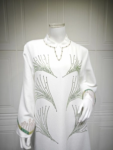 Detail of white crepe dress featuring pearls and green rhinestone starburst patterns