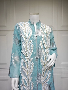 Detail eines mintblauen Kaftans mit Silberfoliendruck und 3D-Stickerei in Weiß
