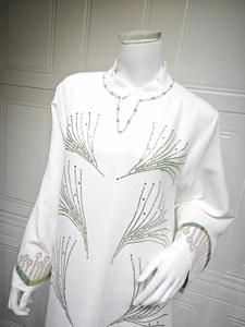 Close-up of white jacquard dress with rhinestones, pearls and floral embroidery details