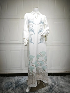 Detailed embroidery and blue pattern on white long-sleeve abaya dress on a mannequin