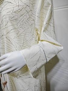 Detail of jacquard fabric with leaf texture and sequined flared sleeves on abaya dress