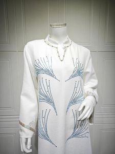 Close-up of white jacquard dress featuring V-neckline with blue beaded fan patterns