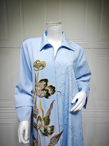Detail of light blue jacquard dress with floral sequin embroidery and pleated texture