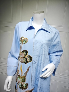 Detailed embroidery with sequins and leaf patterns on a light blue long-sleeved dress