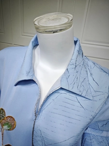 Close-up of sequin floral embroidery and silver piping on a light blue dress bodice