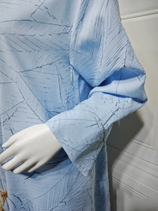 Macro detail of light blue jacquard fabric with leaf-vein pleats and silver cuff trim