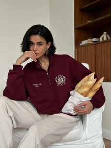 Detail of burgundy polo sweatshirt with quarter-zip collar and varsity print logo