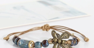 Detailed macro view of handmade ceramic bracelet with blue glaze beads and bronze butterfly
