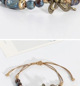 Close-up of handmade ceramic beads and antique bronze butterfly charm on woven bracelet