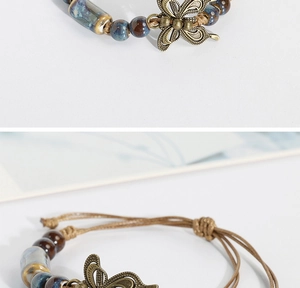 Detail of handmade ceramic bead bracelet with bronze butterfly charm and woven cord