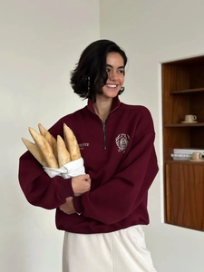 Close-up of a burgundy half-zip polo sweatshirt featuring collegiate shield embroidery