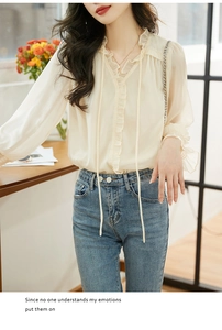 Detail view of cream ruffle V-neck blouse with lantern sleeves and light blue jeans